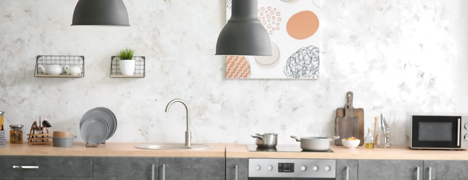 A bright modern kitchen with a stainless steel sink, oven, and prep surfaces