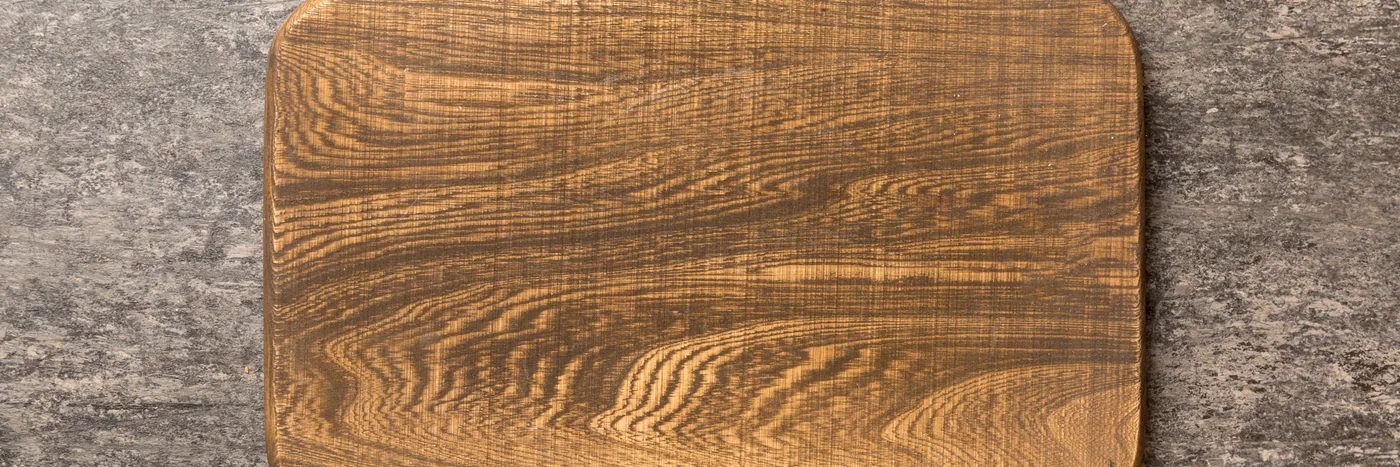 A plain cutting board on a cement worktop, seen from above.
