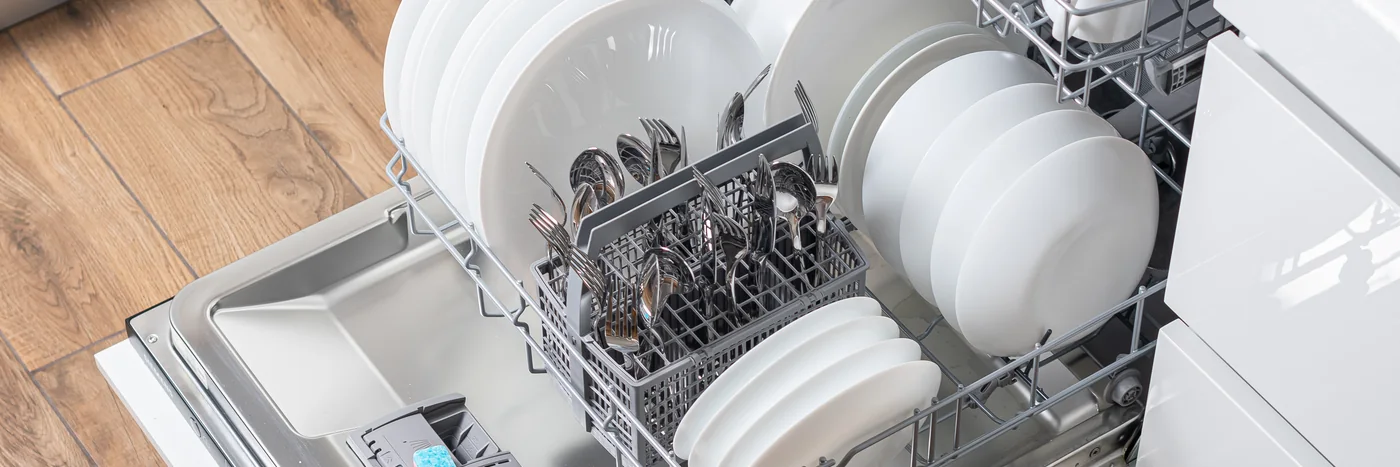 An open dishwasher loaded with clean plates and utensils.